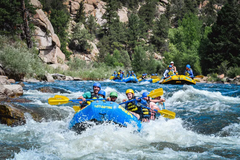group smiling and laughing as they paddle down the Arkansas River