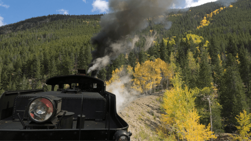 steam engine traveling along tracks through Colorado mountains and fall foliage