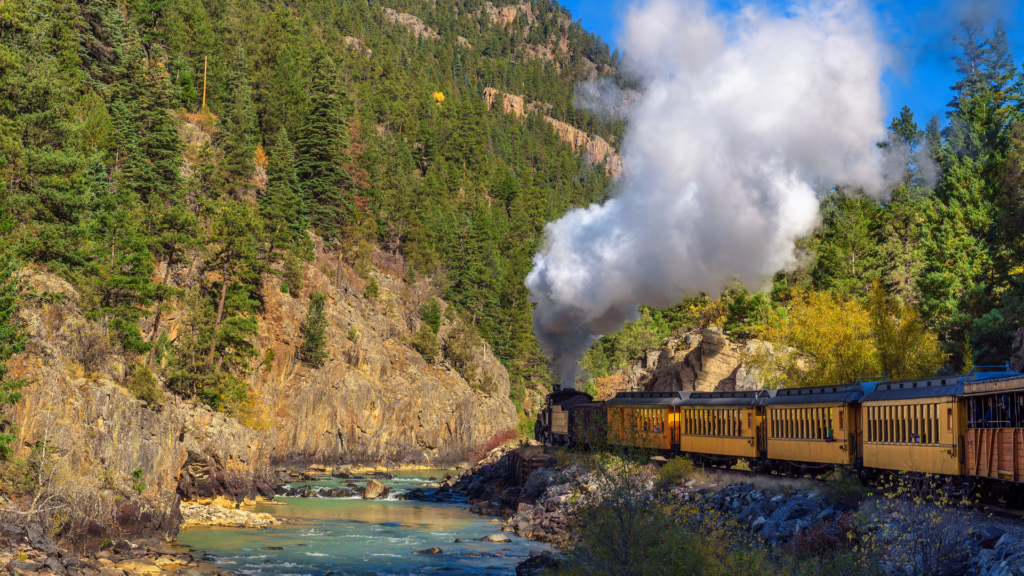 train traveling through Colorado mountains along stream