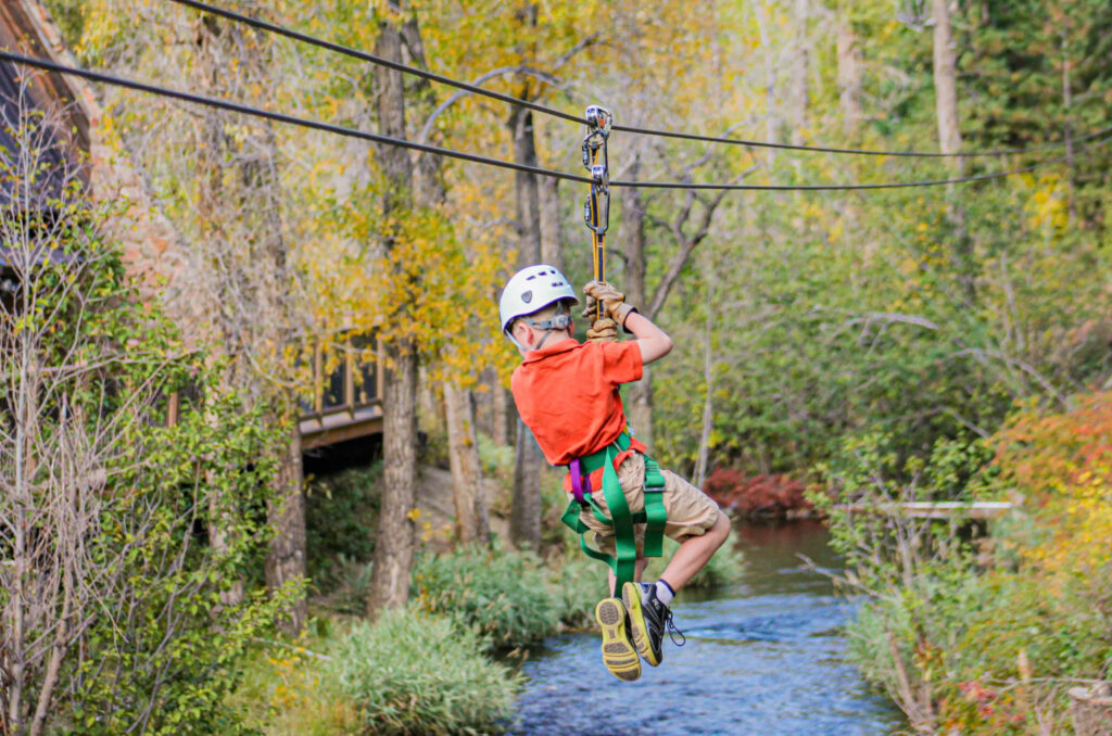 Child ziplining over the Chicago Creek on AVA's cliffside zipline course.