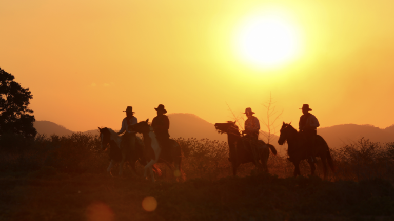 group horseback riding into sunset