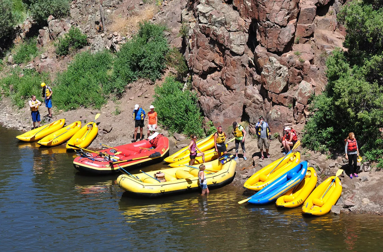 nine ducky rafts and two whitewater rafts pulled up on the side of the river 
