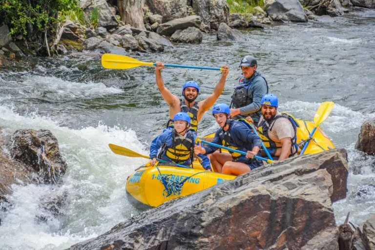 group paddling between rocks on the Clear Creek, as one member raises paddle above his head