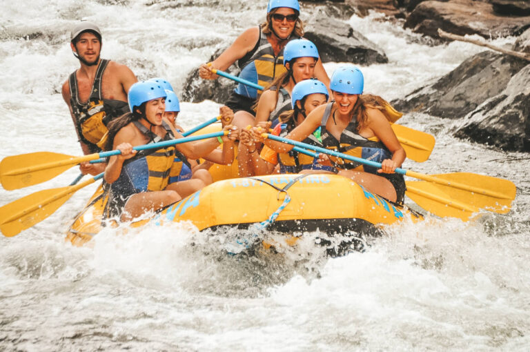 group smiling and rafting through whitewater