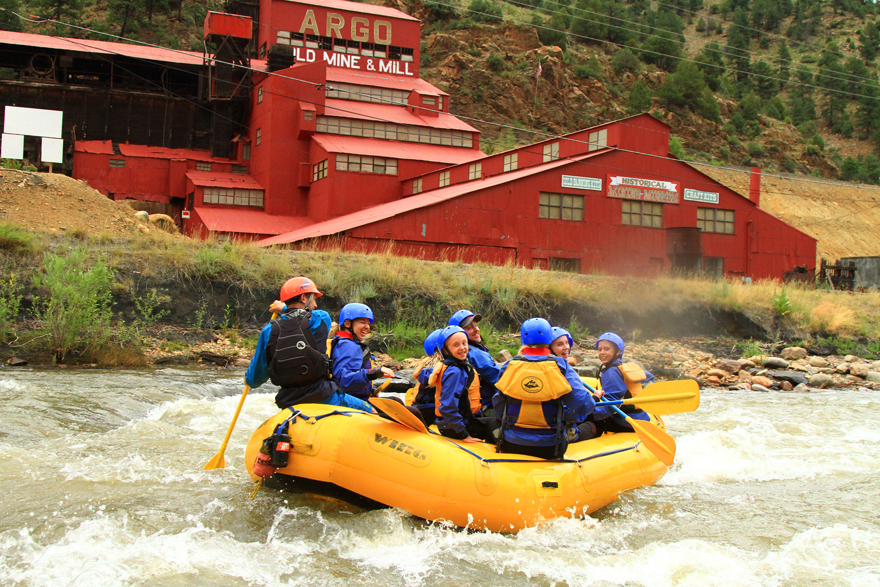 A yellow raft full of people in front of the Argo Mine in Idaho Springs, Colorado