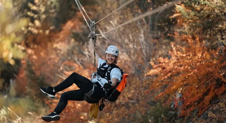 Person ziplining through Colorado fall foliage