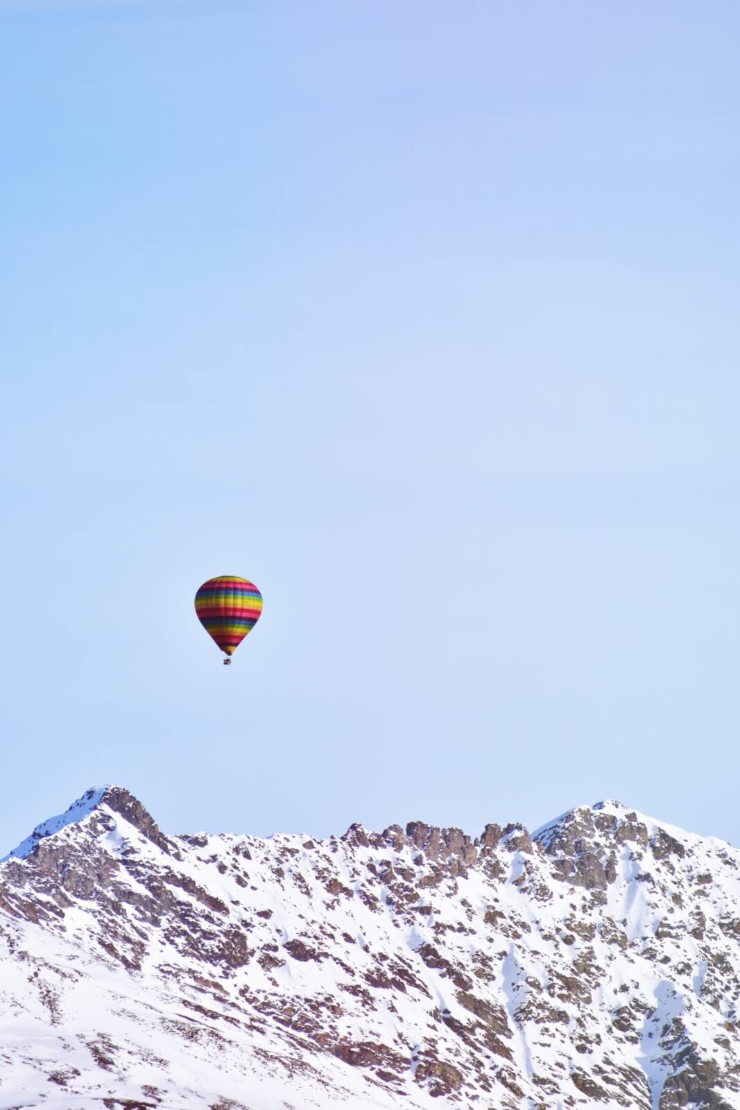 Hot air balloon over snow mountain peaks with the sky in the background