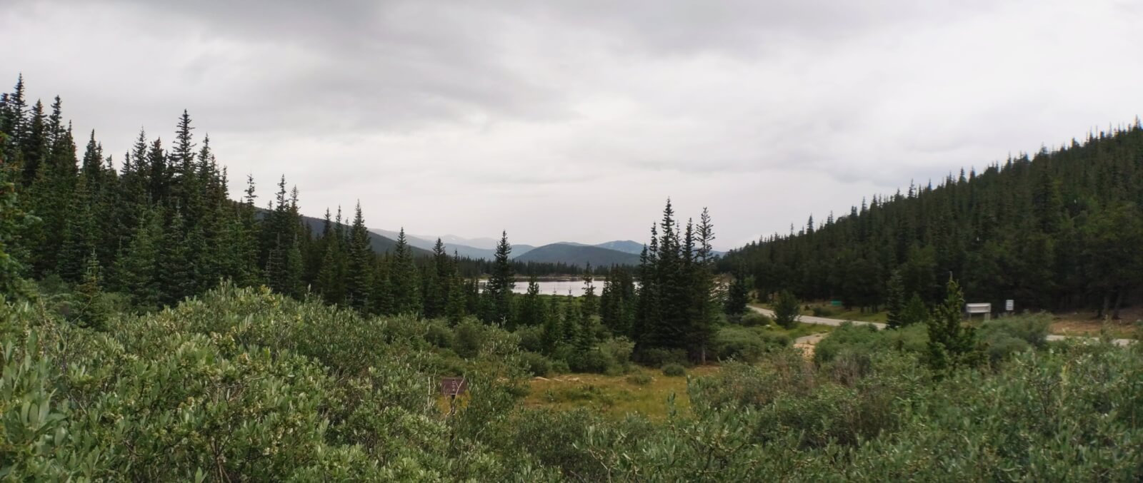 Squaw pass in the summer on a cloudy day with green foliage and a lake in the back