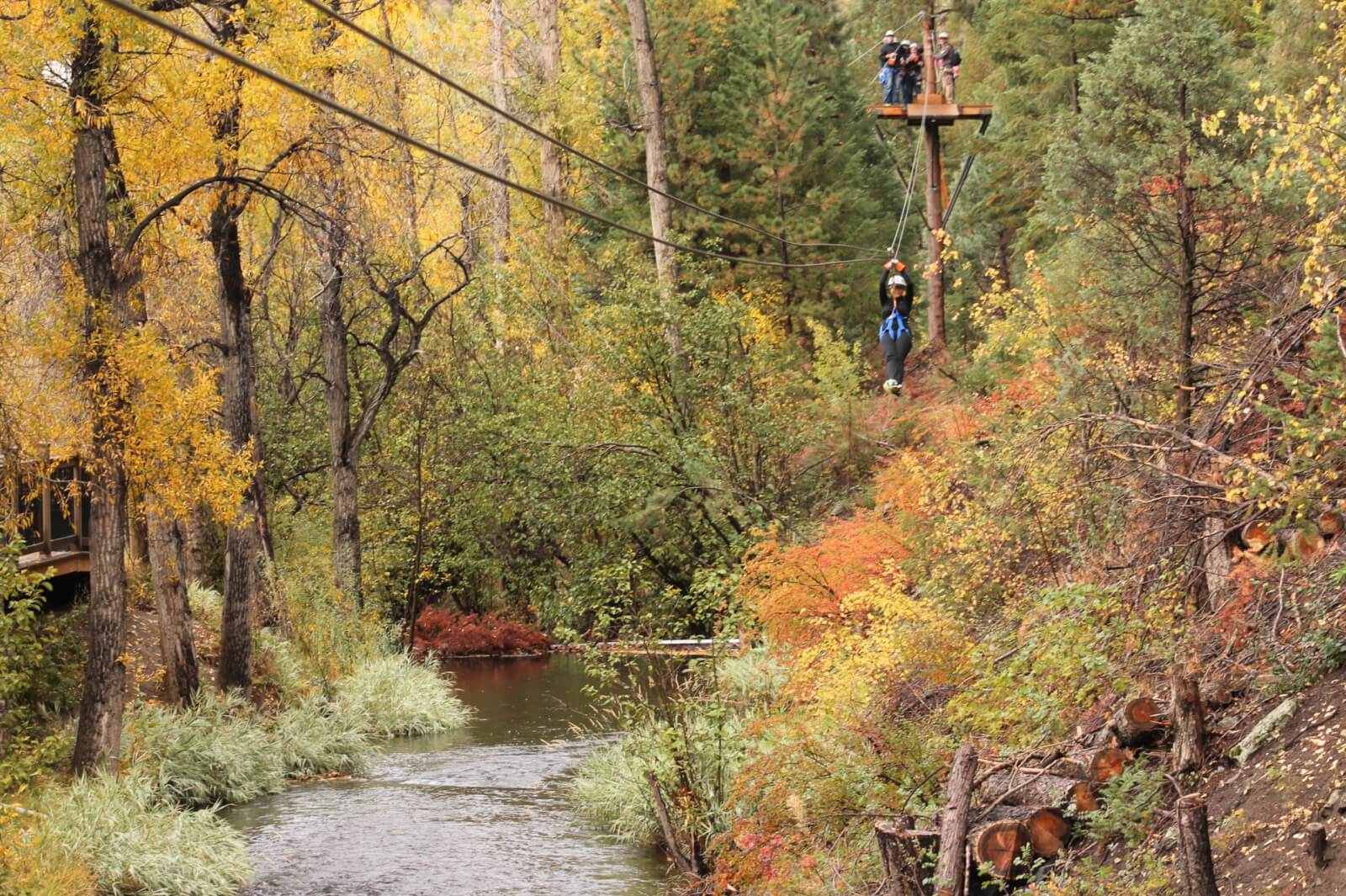 fall ziplining woman zipping over Chicago Creek.