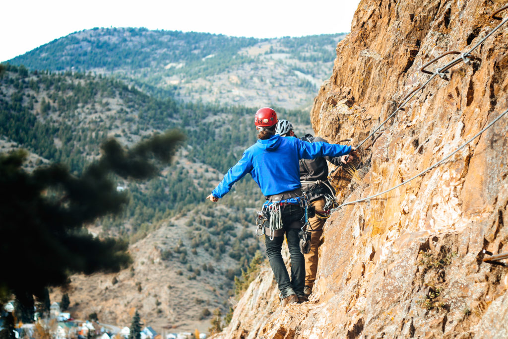 man holding his hand off the cliff on the Mount Evans Via Ferrata Course