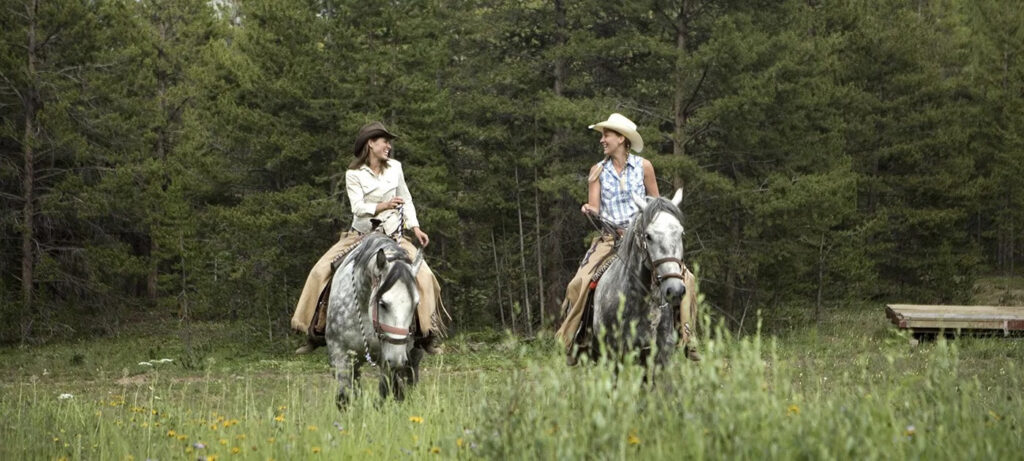 Women riding horses in the backcountry.