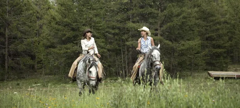 Women riding horses in the backcountry.