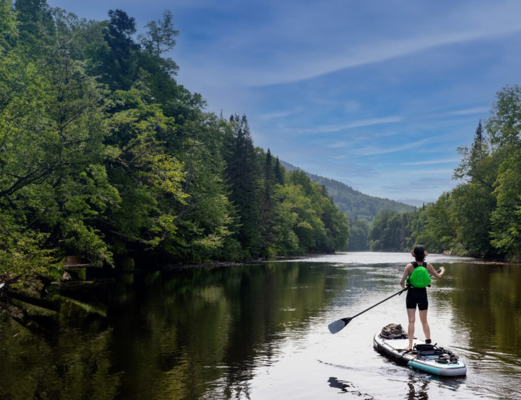 Woman paddling stand up paddleboard down a river in Colorado