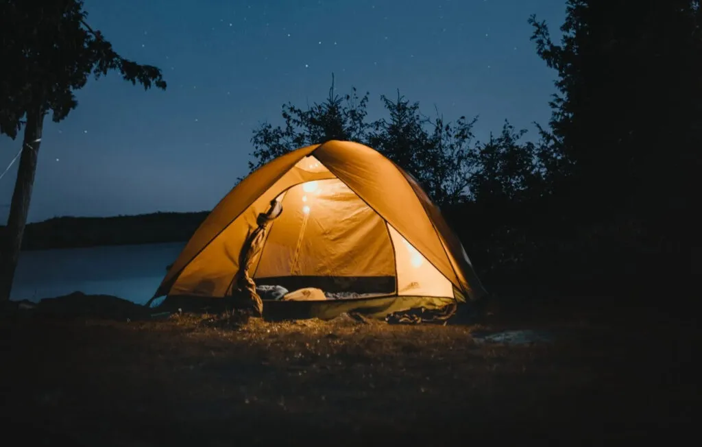 Tent on a lake shore at dusk.