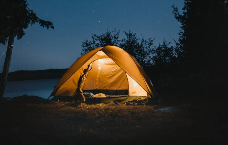 Tent on a lake shore at dusk.