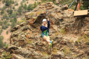 Child ziplining from the cliff face on AVA's cliffside zipline course.