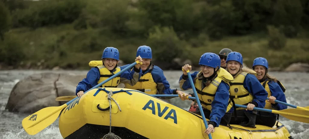 Family smiling and laughing as they paddle the Arkansas River.