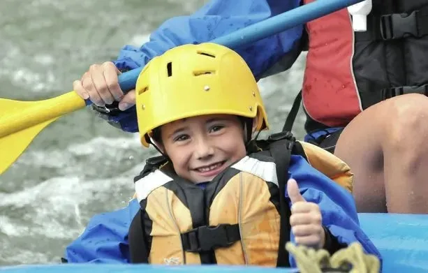 Young boy giving a thumbs up during a waterwater rafting trip.