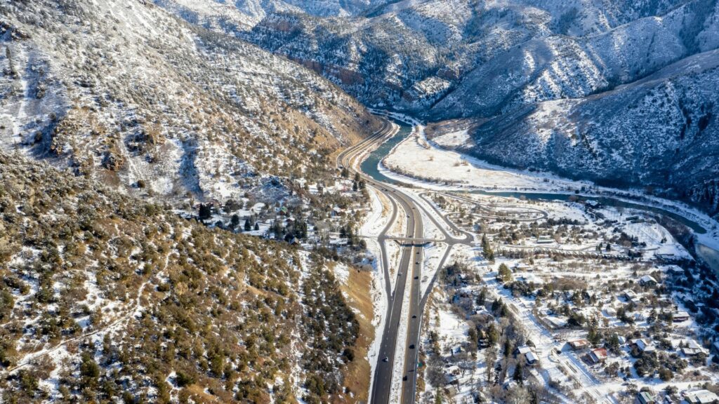 view of Glenwood Springs, the highway, and snow dusted mountains from above