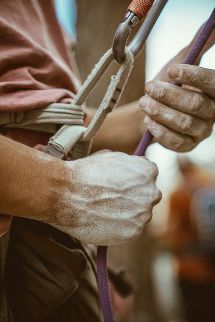 Close up image of a man's chalked hands fixing ropes.