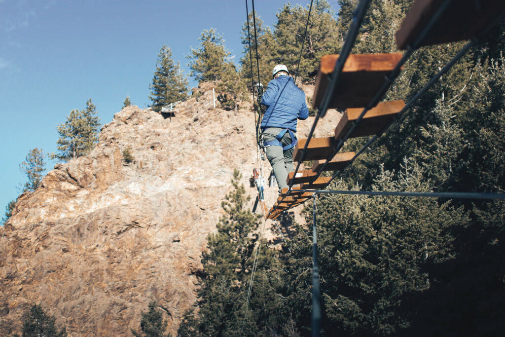 Man walking across hanging bridge on the Mount Blue Sky Via Ferrata course