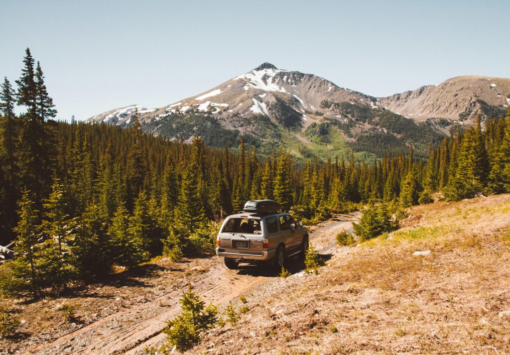 SUV driving on dirt road in Colorado wilderness.