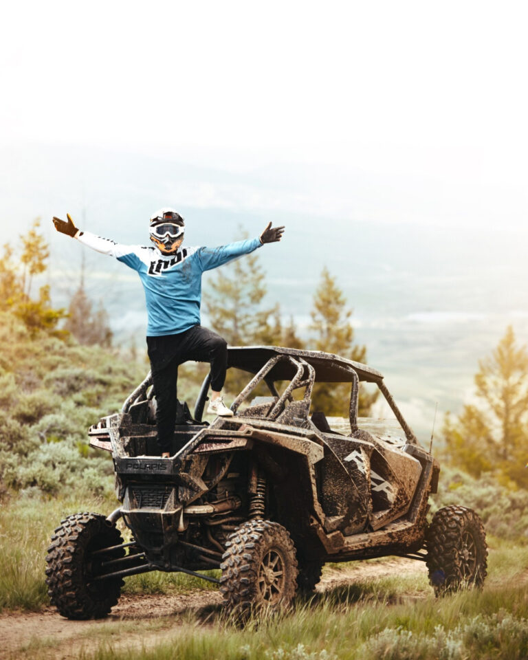 Guest standing on top of a RZR UTV rental with arms spread open.