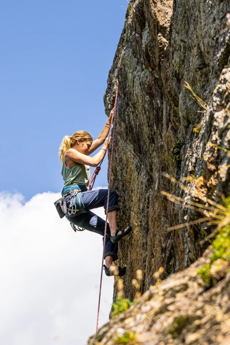 Woman top rope climbing the cliffside.