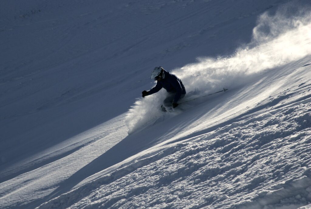 person skiing down fresh powder mountain slope