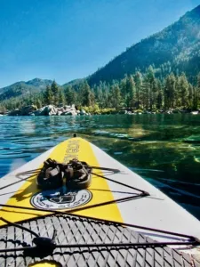 paddleboard in the middle of a lake with chacos resting on top, smaller version