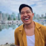 Man smiling in front of city skyline and waterfront