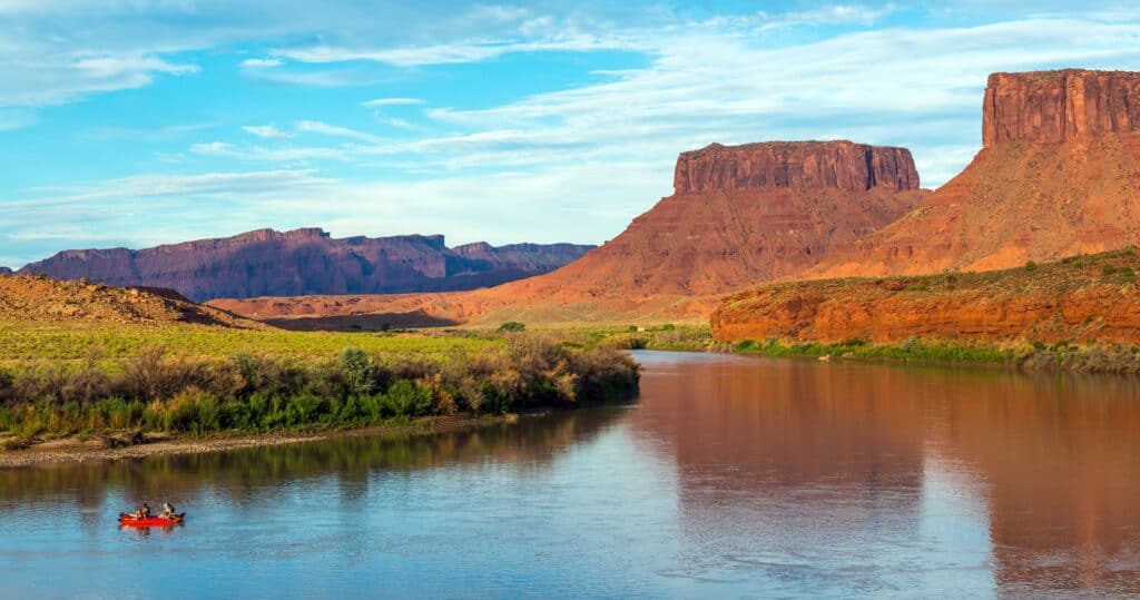people rafting on colorado river with mountains in the background